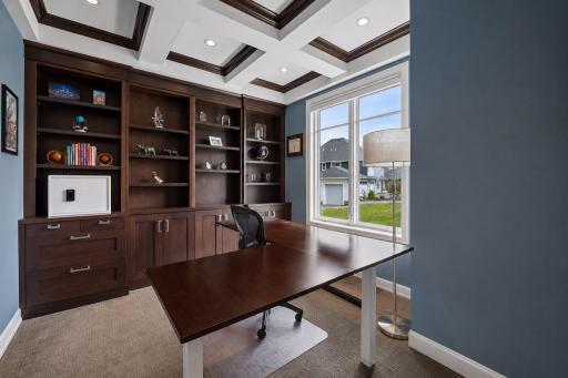 This main level office boasts a wall of built-ins and customized coffered ceilings.