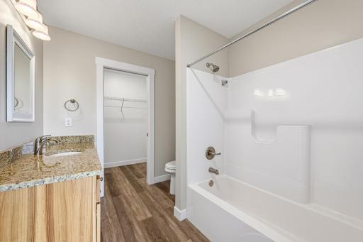 The full private ensuite bathroom features a granite topped vanity, durable LVP flooring, and a tub/shower combo.