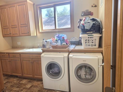 Main floor laundry room features washing sink, folding table and plenty of storage. Garage is accessible through laundry room.
