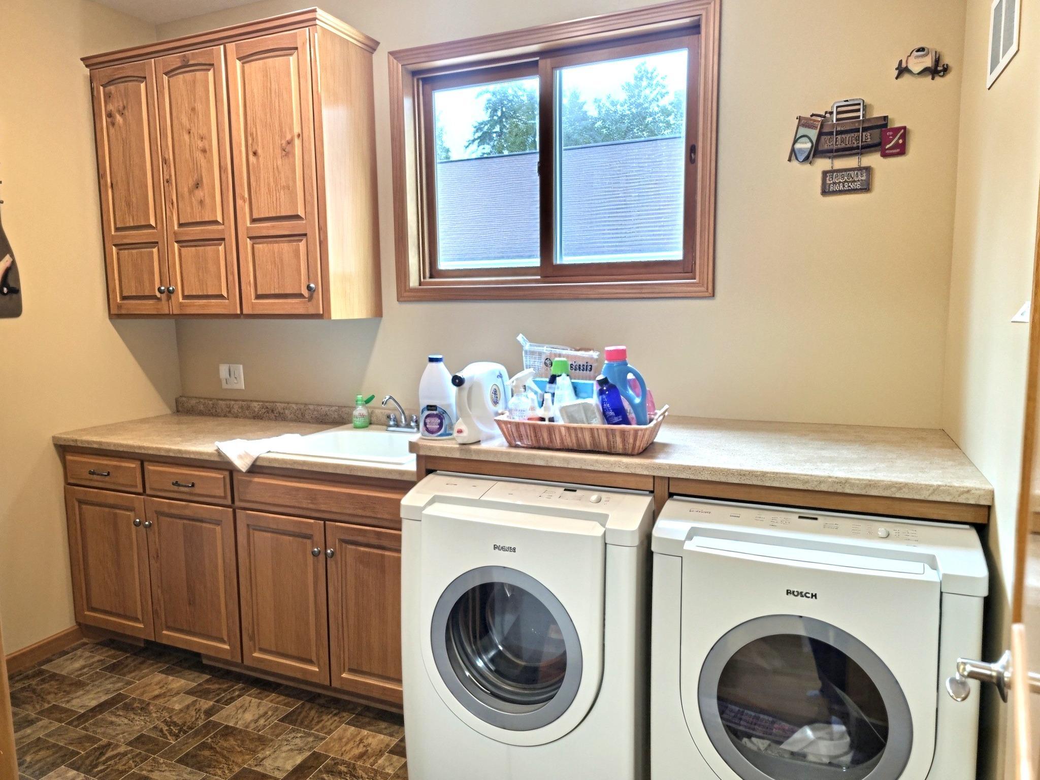 Main floor laundry room features washing sink, folding table and plenty of storage. Garage is accessible through laundry room.