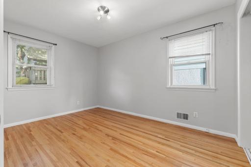 Comfortable bedroom with hardwood flooring and a fresh, neutral palette.