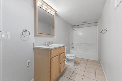 Full bath with tile flooring, vanity storage, and a clean, functional layout.