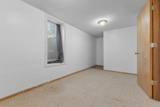 Lower-level room with soft carpet and flexible space for relaxing or hobbies.