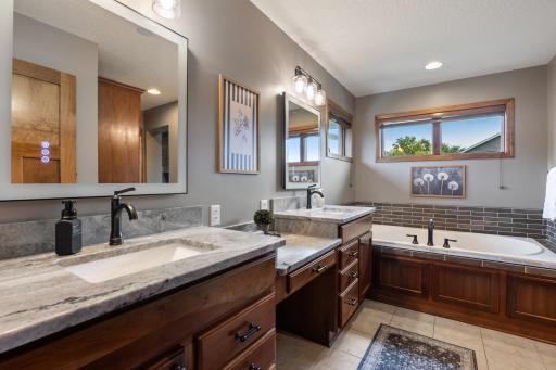 Newly remodeled primary ensuite with granite counters, lighted mirrors, updated fixtures and tile.