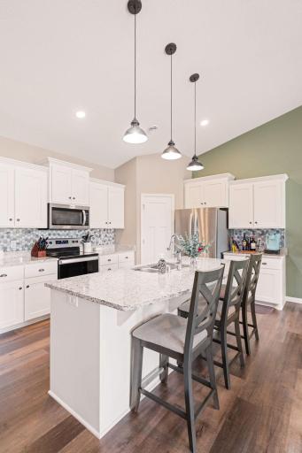 Kitchen features center island, white cabinetry, corner pantry and granite countertops