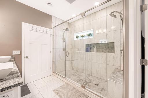 WOW!! Custom walk-in shower with floor to ceiling tile, dual head shower heads and built-in bench