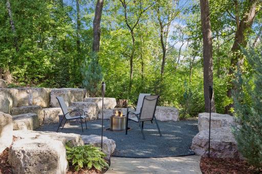 Elevated stone waterfall style natural seating area that features a perfect fire pit gathering spot.