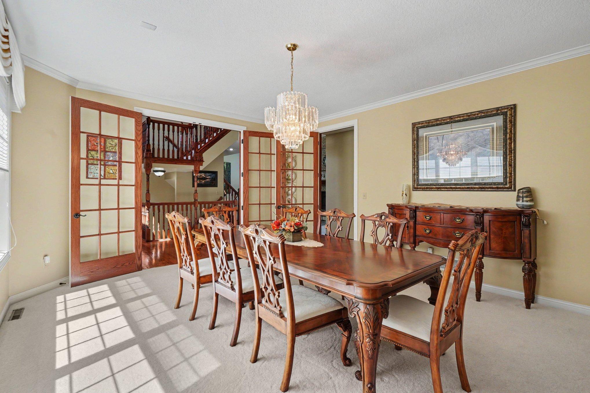 Elegant formal dining room featuring French doors, a sparkling chandelier and generous space for hosting family and friends. A graceful setting for everything from holiday dinners to intimate gatherings.