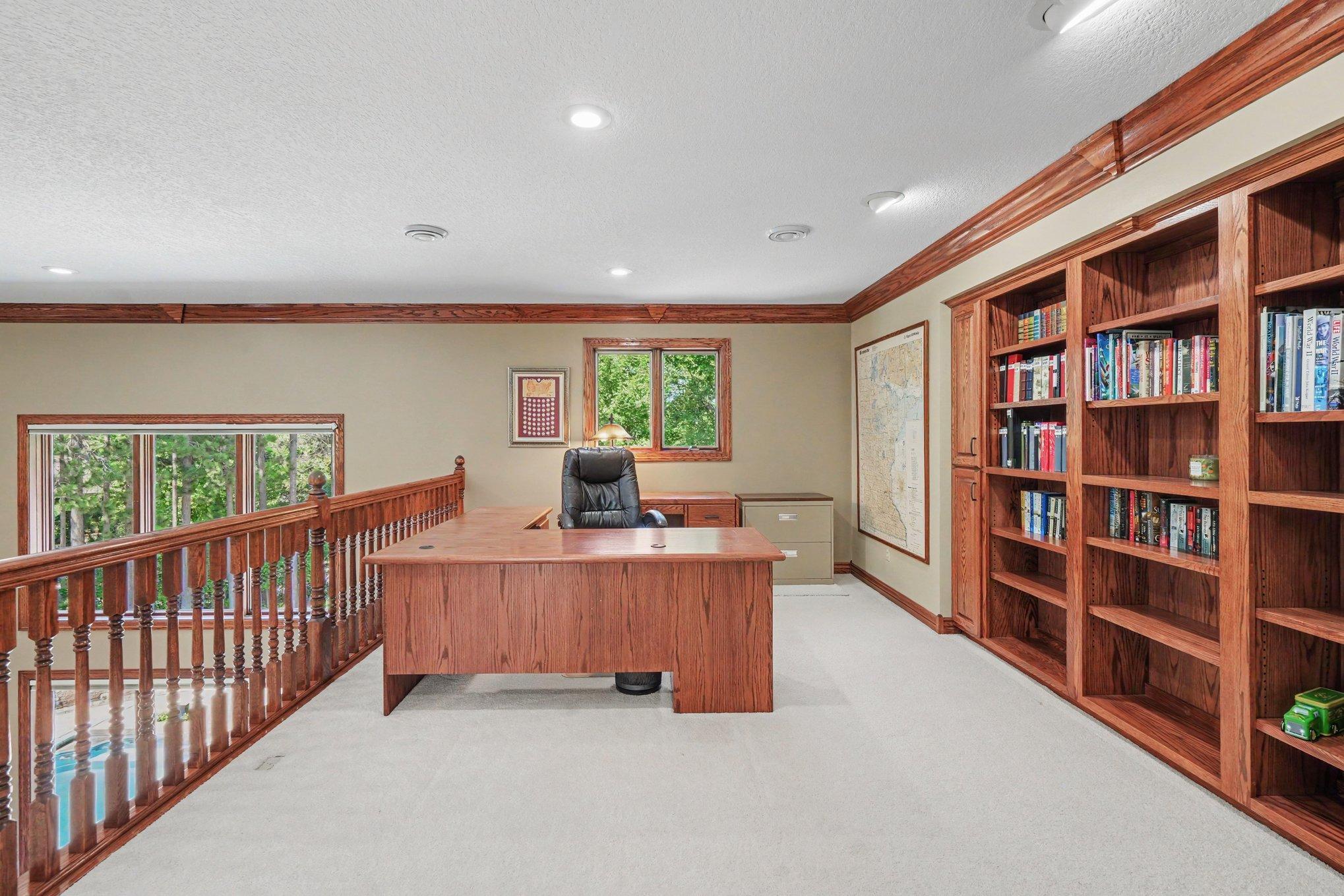 A spacious upper-level loft offers an ideal second office, study or homework area with custom built-in bookcases and abundant natural light. The open railing overlooks the great room below, keeping the space connected while still feeling private.