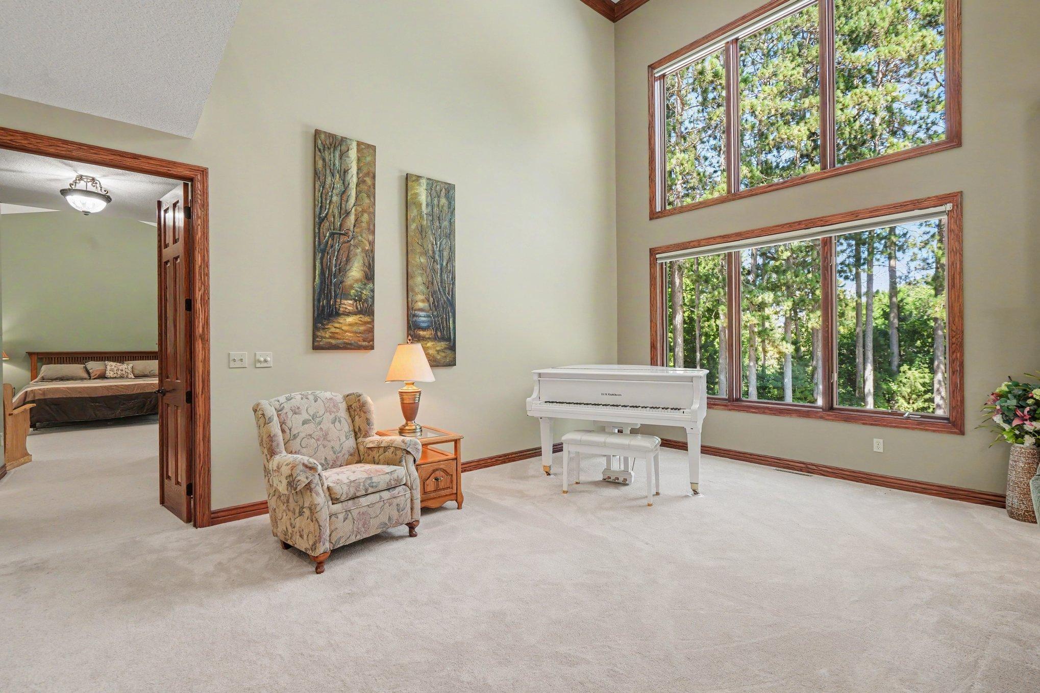 A serene sitting area beside the great room offers a peaceful spot to relax, read or enjoy music while taking in the private, tree-lined views. Two-story windows fill the space with natural light and create a beautiful connection to the outdoors.