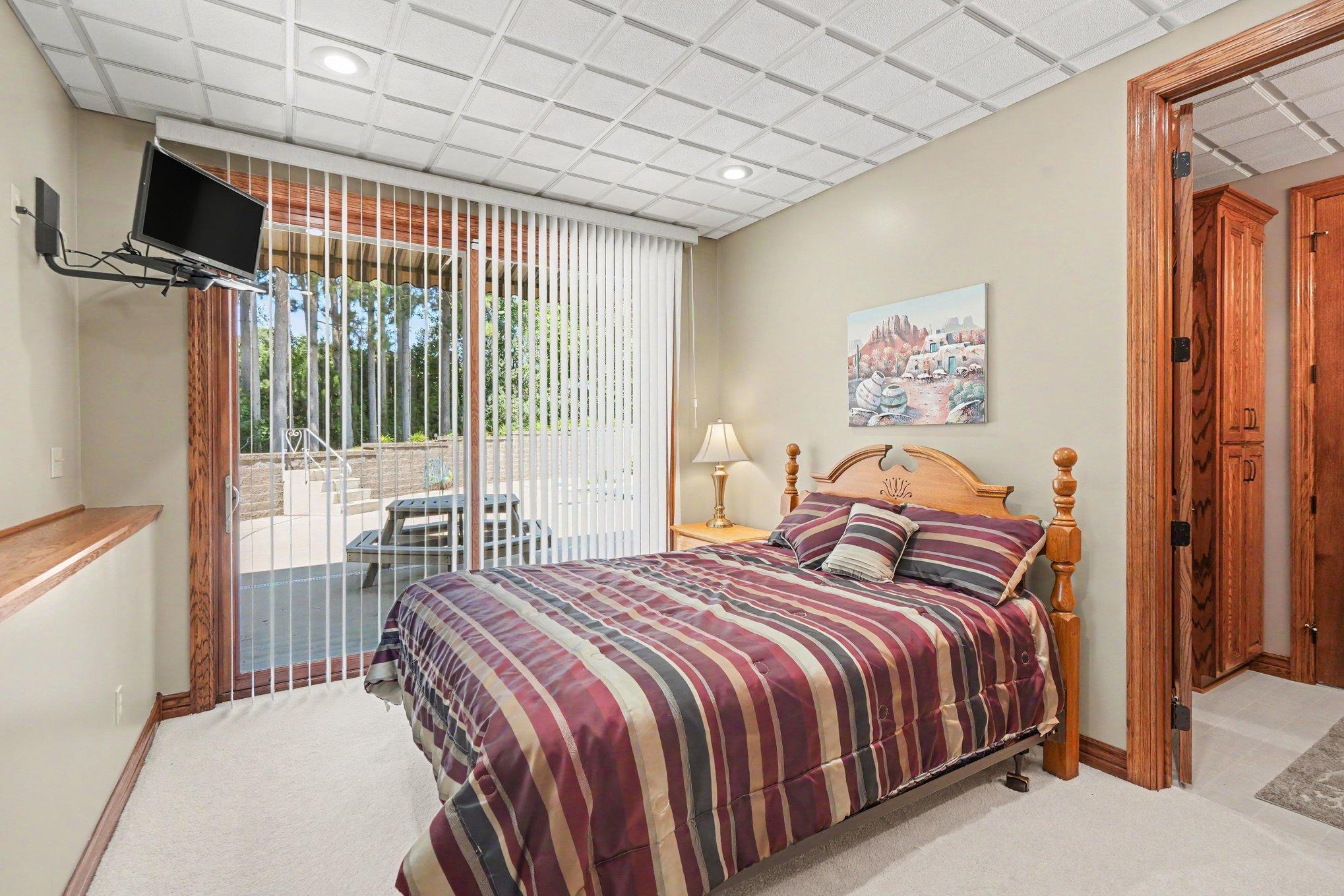A private lower-level bedroom offers convenient walkout access to the pool area, making it ideal for guests or extended family. Nearby bath access and abundant natural light add comfort and versatility to the space.