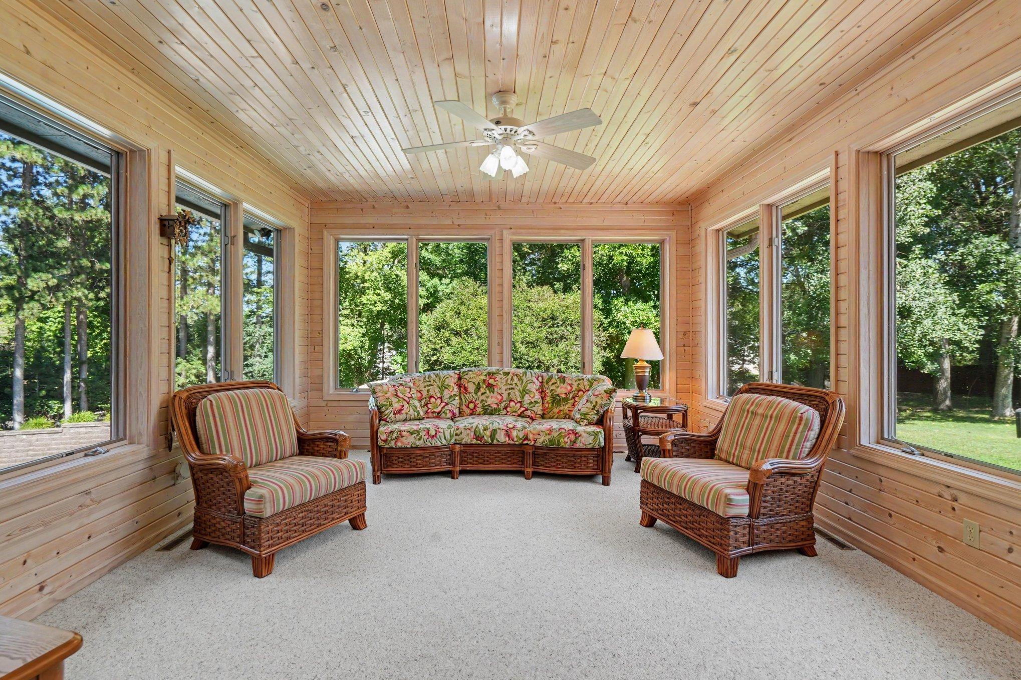 The sun-filled four-season porch overlooks the pool, patio and deck, offering a peaceful place to relax in every season. Surrounded by windows and natural wood finishes, this inviting space brings the outdoors in while extending your living area.