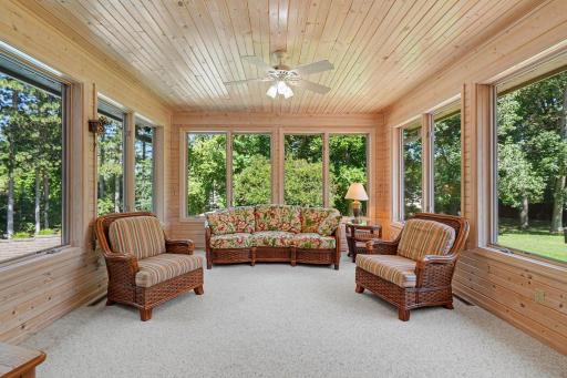 The sun-filled four-season porch overlooks the pool, patio and deck, offering a peaceful place to relax in every season. Surrounded by windows and natural wood finishes, this inviting space brings the outdoors in while extending your living area.