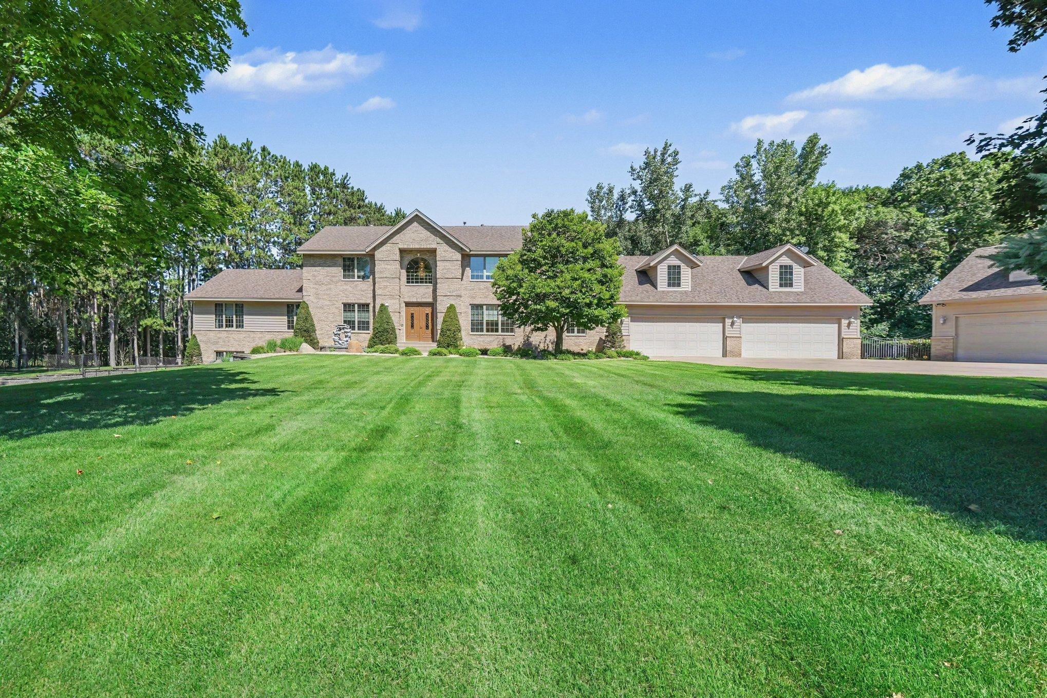 A beautifully manicured lawn creates a striking approach to this expansive custom home framed by mature trees and a peaceful private setting. The impressive facade and dual garage configuration showcase the scale, versatility and estate-like presence