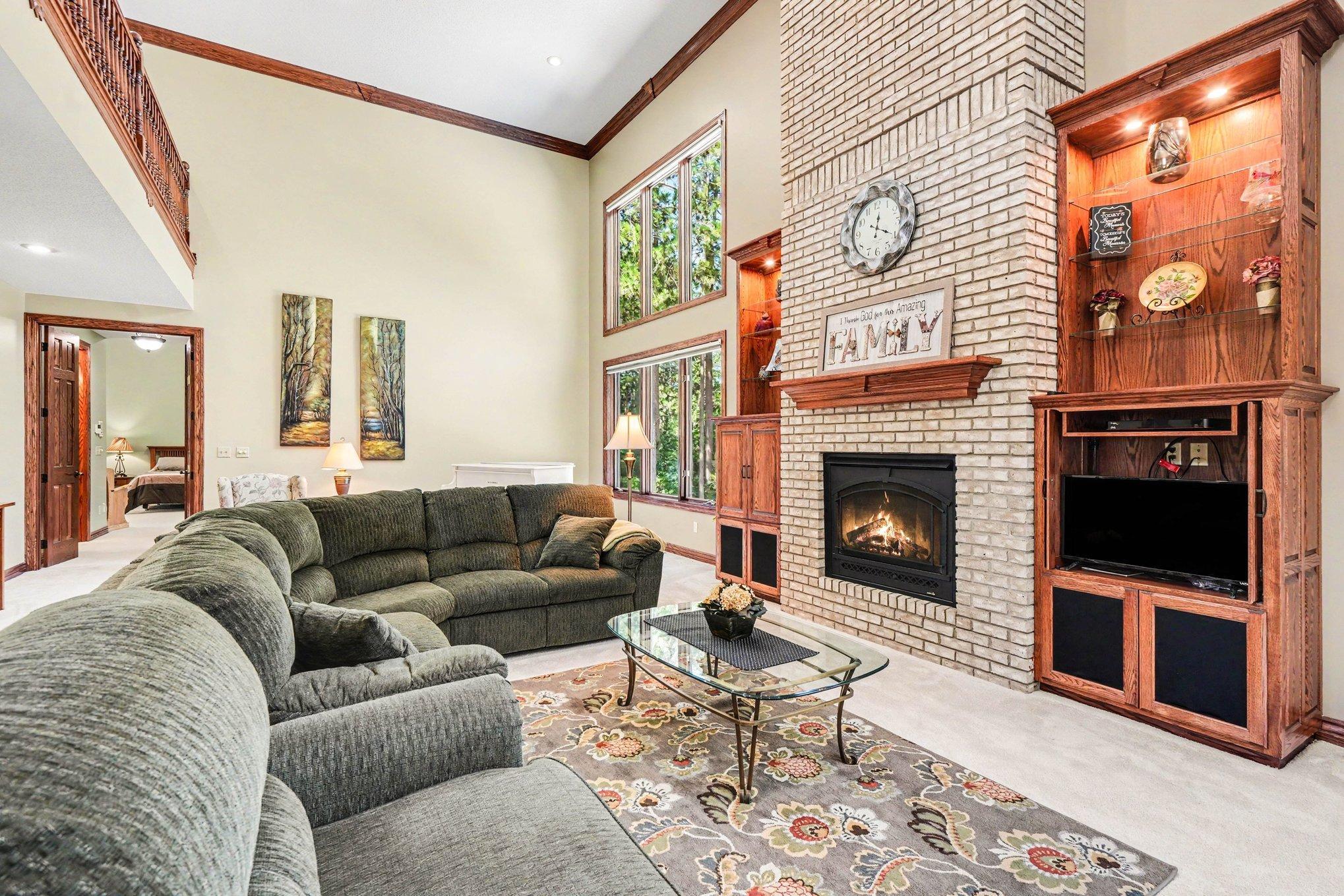 Soaring ceilings and an open upper-level overlook give this great room an impressive sense of scale, while the gas fireplace and custom built-ins add warmth and character. Expansive windows bring in abundant natural light and pool views.