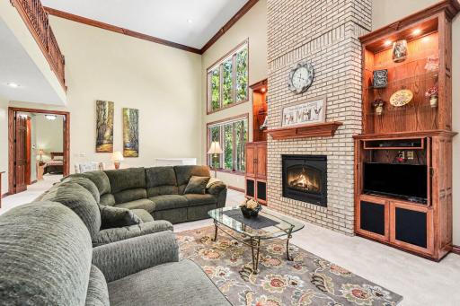 Soaring ceilings and an open upper-level overlook give this great room an impressive sense of scale, while the gas fireplace and custom built-ins add warmth and character. Expansive windows bring in abundant natural light and pool views.