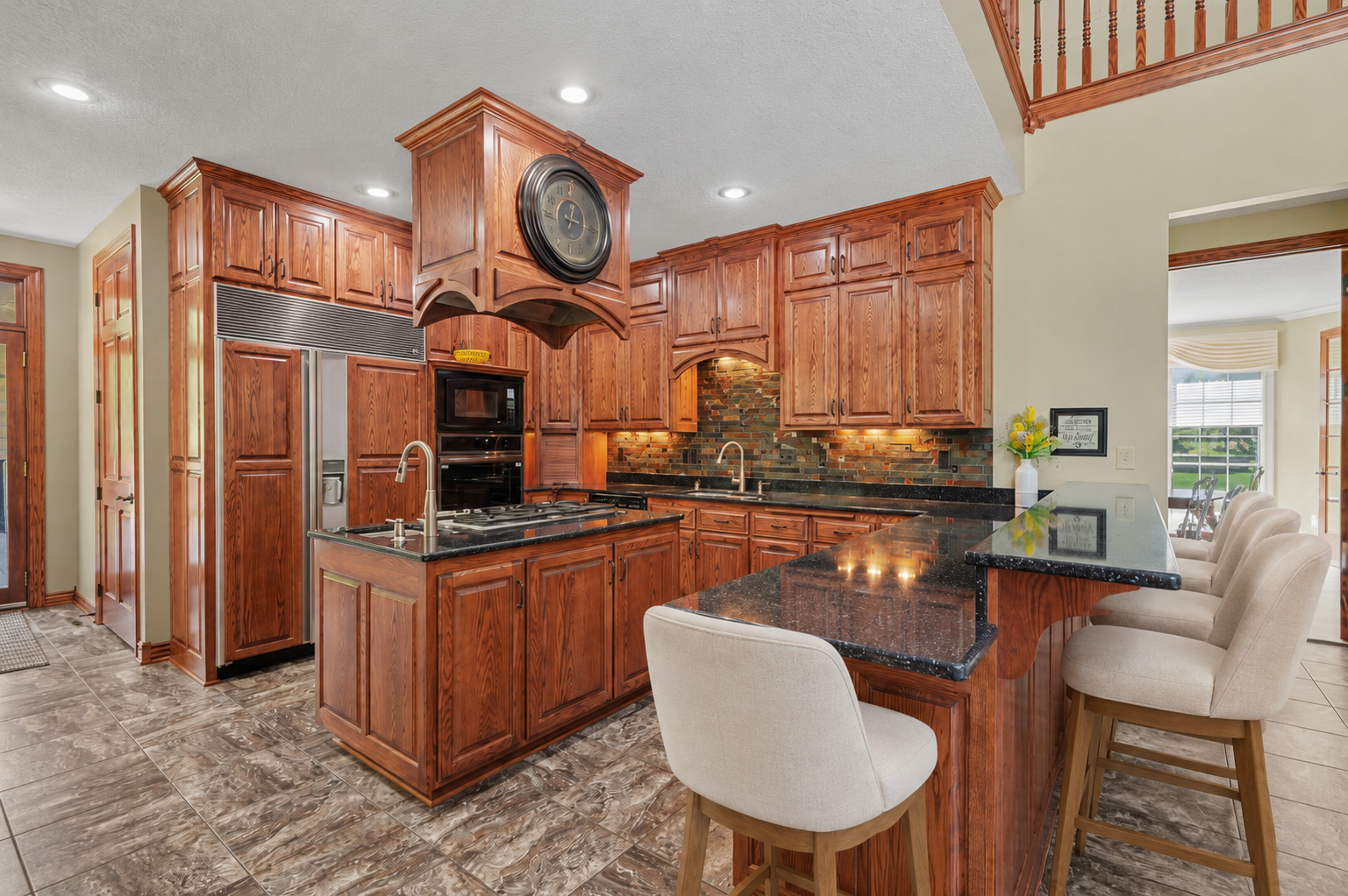 A premium Sub-Zero refrigerator blends seamlessly into the custom cabinetry, adding high-end function to this beautifully designed kitchen. The generous breakfast bar provides comfortable seating for casual meals, conversation and entertaining.