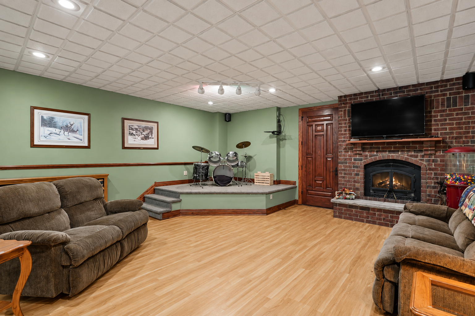 A spacious lower-level family room is ready for fun with a raised stage perfect for karaoke, music or performances. The brick fireplace adds warmth and character, creating an inviting space for gatherings and entertaining.