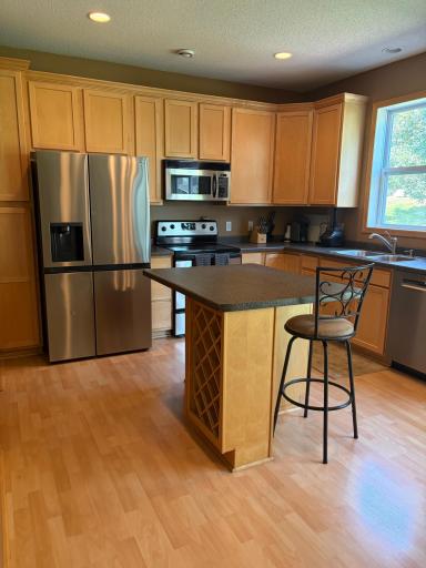 Kitchen w maple wood work, tall cabinets, wine in the island, stainless steel appliances
