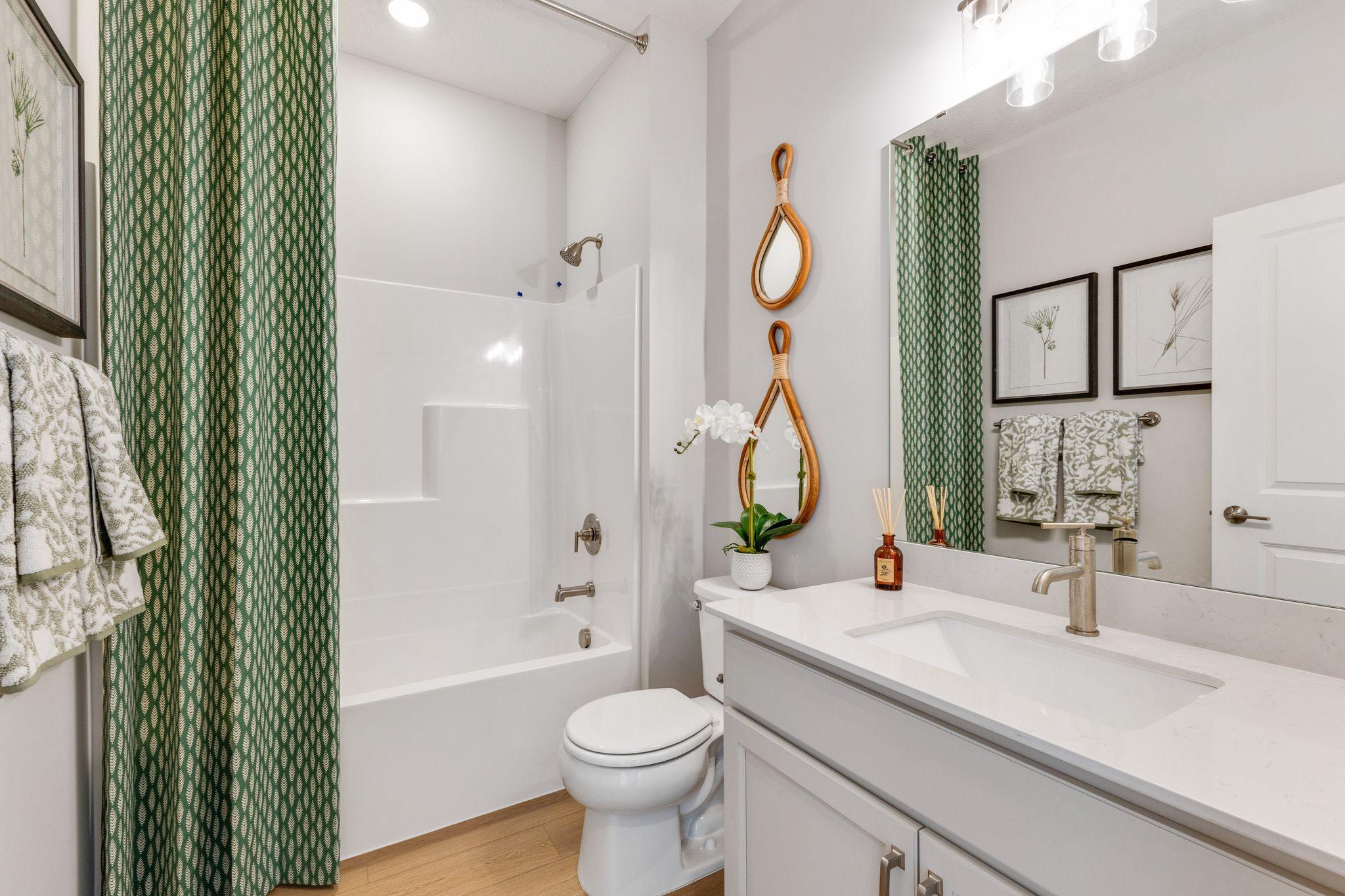 Secondary bath features a shower/tub combo with quartz countertops. Photo of model home, colors and finishes may vary.