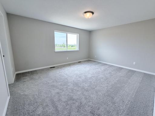 PHOTO OF A DIFFERENT HOME WITH SIMILAR PLAN AND FINISHES. Primary Suite features a walk-in closet and private bathroom.