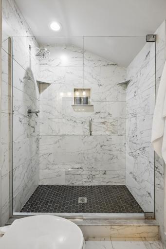 Primary bath with a glass-enclosed shower, elegant tiled walls, and hexagon-tiled shower floor.