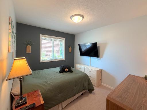 The second upper-level bedroom offers a comfortable retreat with soft natural light from a large window with neutral finishes - perfect for a guest bedroom.