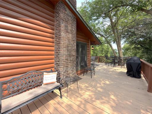 The expansive lakeside deck offers the perfect place to entertain, grill, or simply relax beneath the shade of mature trees while taking in peaceful lake views.