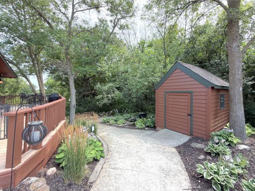 The attractive garden shed blends seamlessly into the beautifully landscaped yard while providing valuable storage space for all your garden and lawn tools.