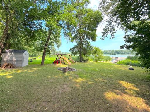 The spacious lakeside level yard offers plenty of room for outdoor fun, complete with a playset, storage shed, and easy access to the shoreline.