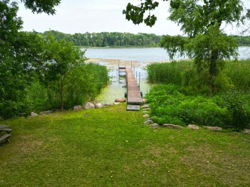 Enjoy peaceful Ramsey Lake views from the spacious level lakeside yard, complete with a private dock and surrounded by towering mature trees for a tranquil setting.