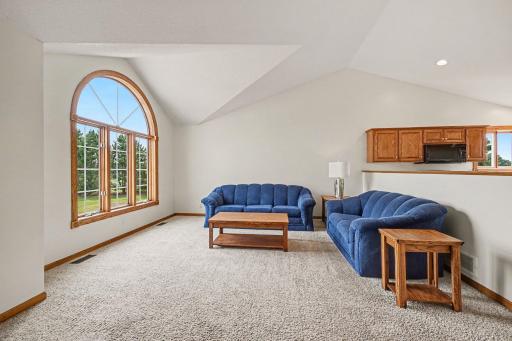 Spacious living room featuring vaulted ceilings and an impressive arched window overlooking the property.