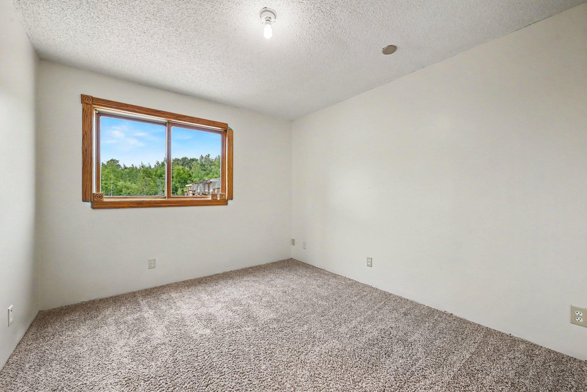 Lower-level bedroom #4 with natural light and views of the property.