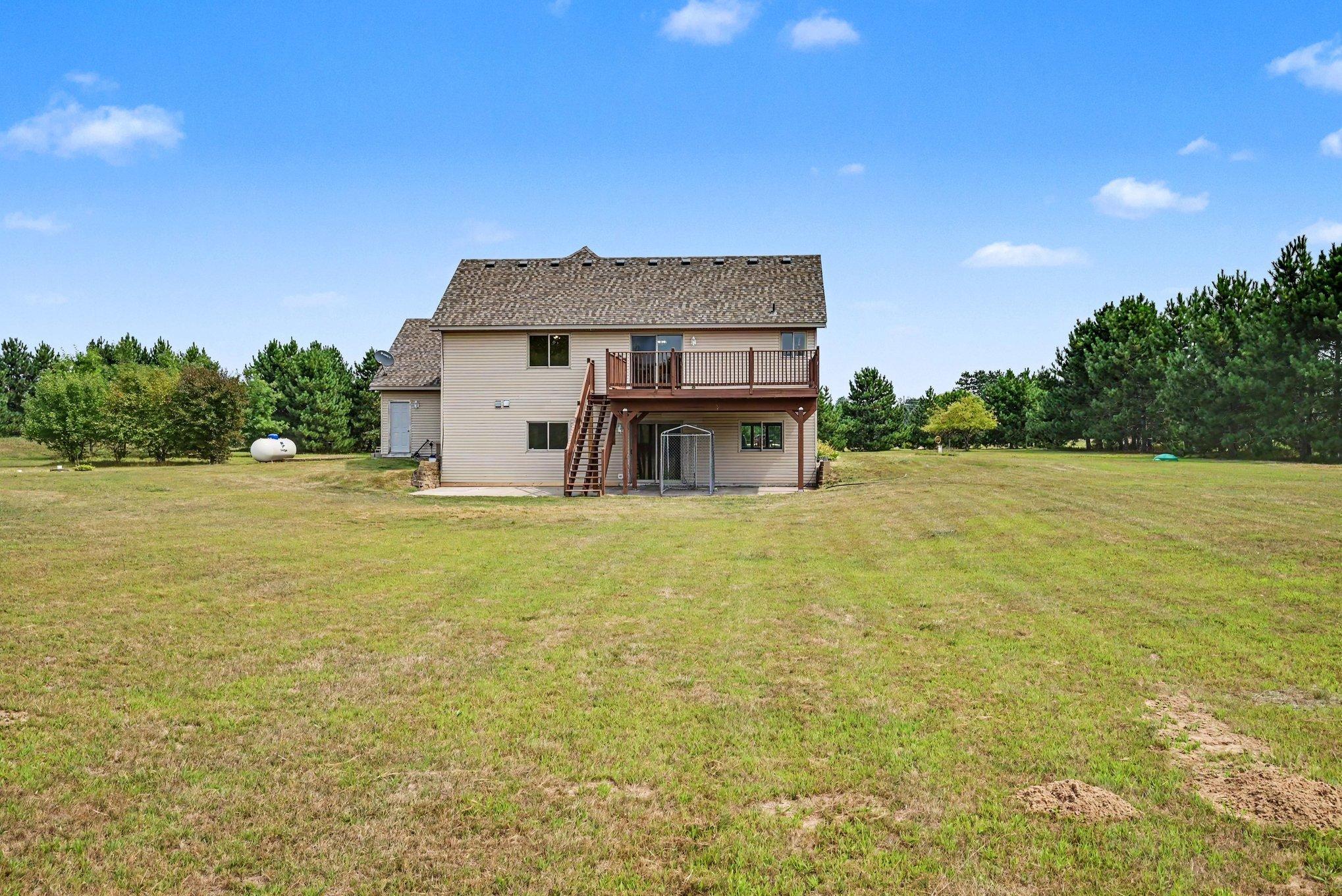 Rear view of the home showcasing the large, open backyard and expansive grounds.
