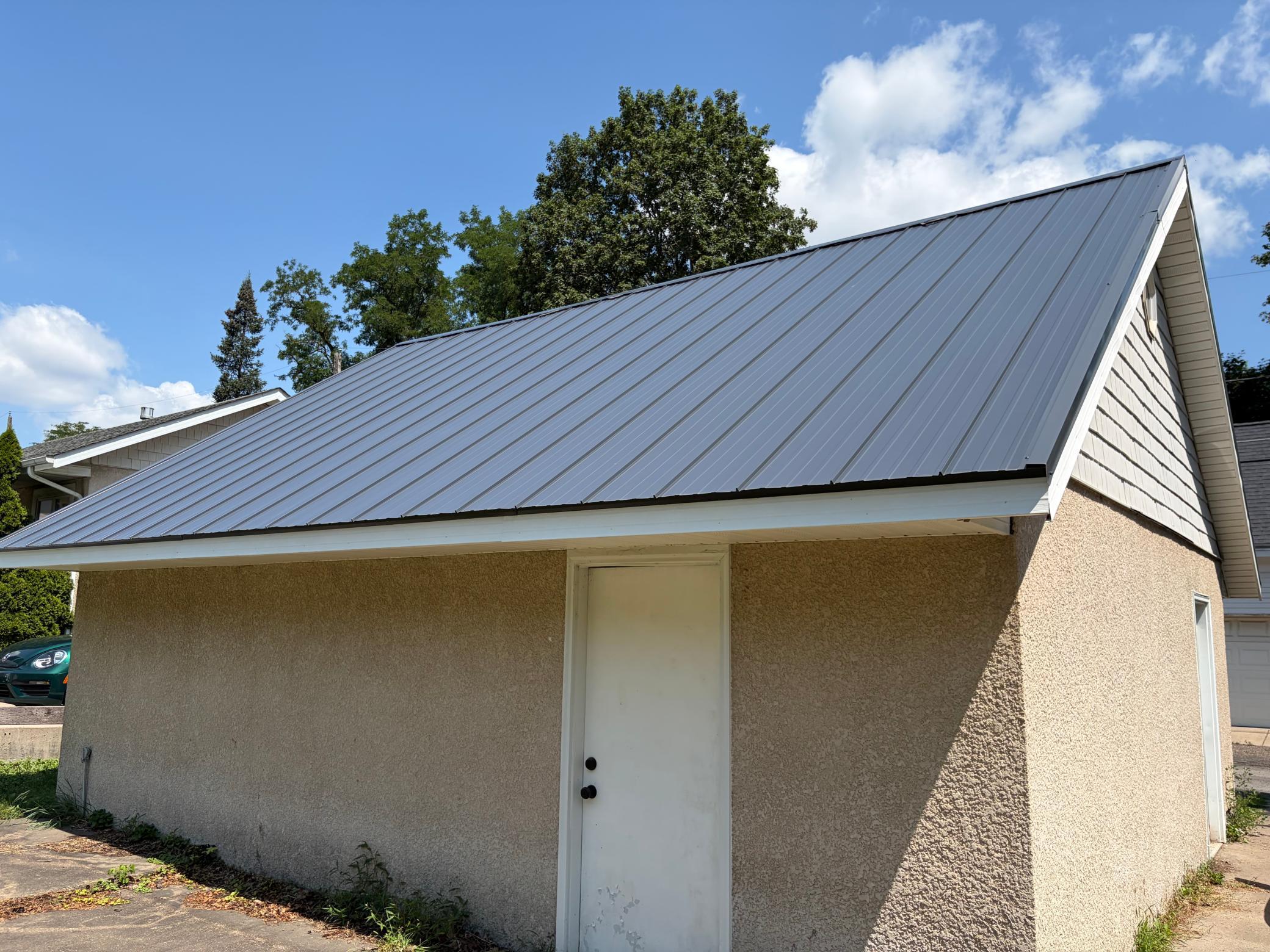 The garage has stucco siding and a newer metal roof.