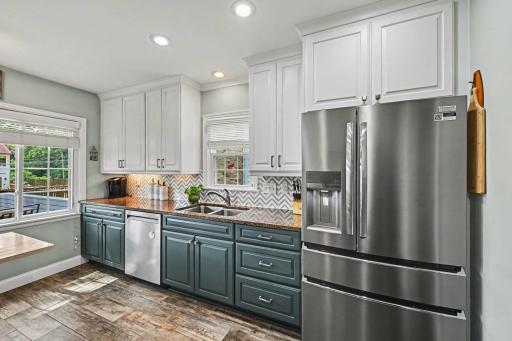 Gorgeous remodeled kitchen with wide plank flooring, stainless steel applainces and new backsplash