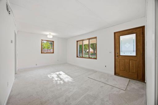 Front door into living room with fresh paint and new carpet.
