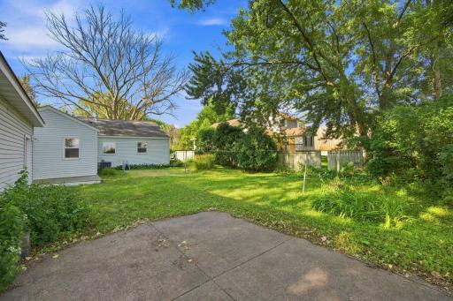 Spacious partially fenced in yard with concrete patio