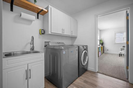 Convenient main level laundry with LVP flooring and built-in storage.