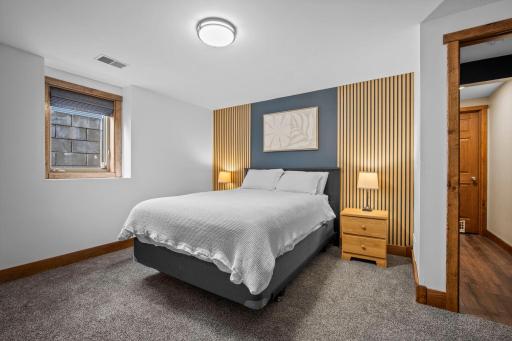 Spacious fifth bedroom with an egress window and stylish wall panel accents.