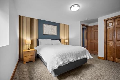 The finished lower level includes a spacious fifth bedroom featuring an egress window and elegant wall panel accents.