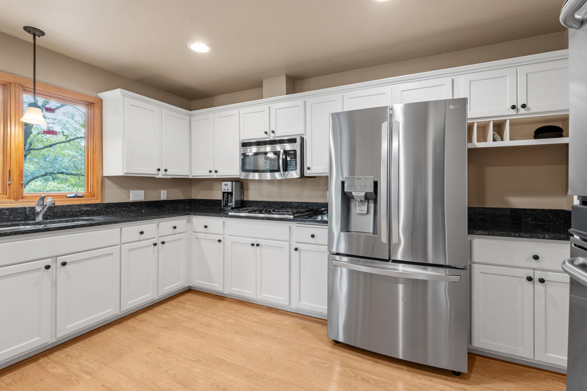 Nicely updated kitchen with custom cabinets, double wall ovens, stainless steel appliances, granite countertops, an undermount sink, and plenty of space! A window overlooks the deck and backyard.