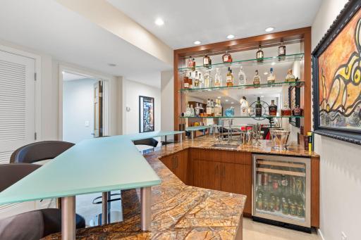 Stylish wet bar complete with a two-tier peninsula with glass countertop.