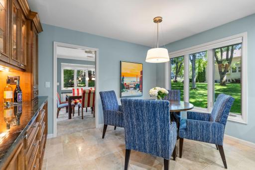 Just steps away, the informal dining area features a serving counter with ambient lighting and glass-front cabinetry.