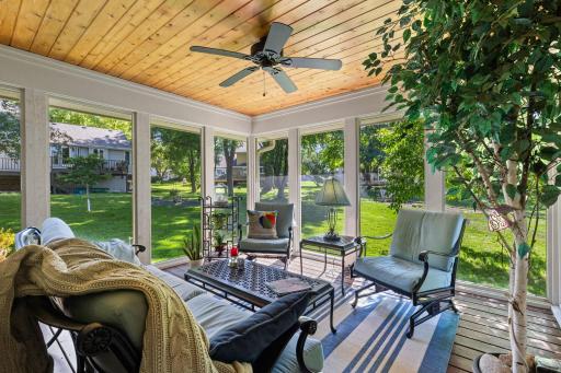 The walkout three-season sunroom extends the living space outdoors with a wood-paneled ceiling and ceiling fan.