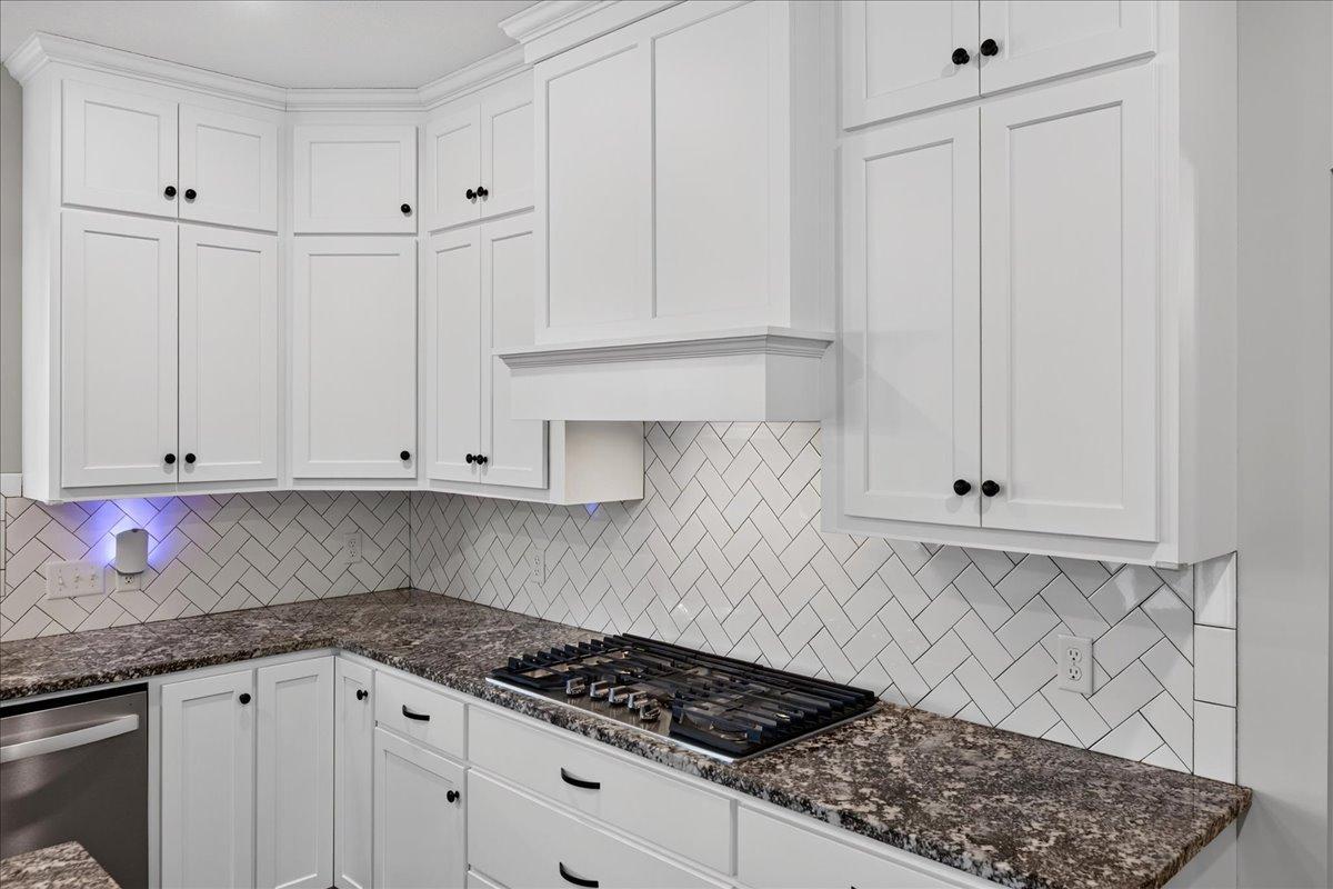 Gas cooktop, cabs to ceiling, herringbone subway tile back splash and granite countertops