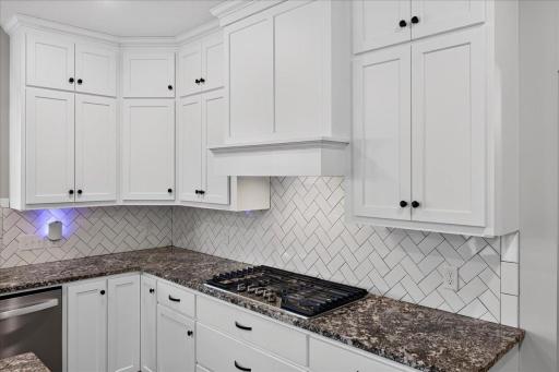 Gas cooktop, cabs to ceiling, herringbone subway tile back splash and granite countertops