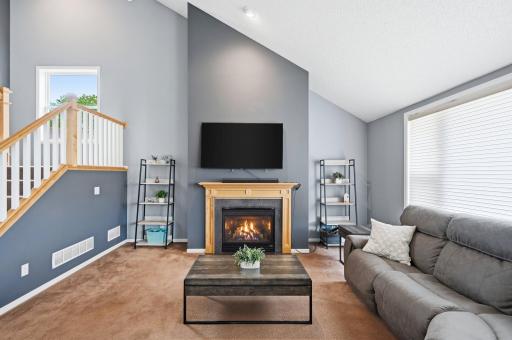 Beautiful fireplace serves as a natural focal point within the main living area, complementing the vaulted ceilings and open-concept design.