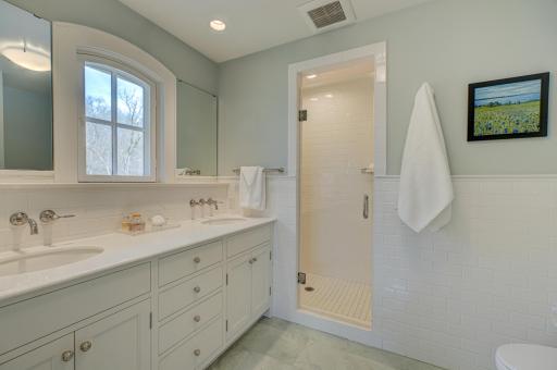 Enjoy spa-like comfort in this private primary bath with double sinks, a tiled shower, and warm heated floors