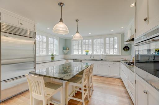 Sunlight pours into this stunning kitchen, where expansive windows showcase serene, wooded views and create an inviting, open feel